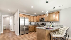 Una cocina moderna con armarios de madera, electrodomésticos de acero inoxidable y una zona de bar con taburetes.