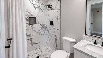 Een badkamer met douche, toilet en wastafel.