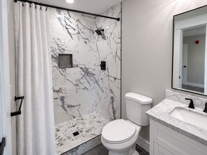 A bathroom with a shower, toilet, and sink.