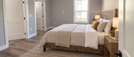 Un dormitorio con cama, ventilador de techo, ventana y mesita de noche con lámpara.