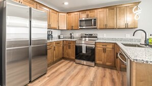 Una cocina moderna con armarios de madera, electrodomésticos de acero inoxidable, encimeras de granito y horno empotrado.