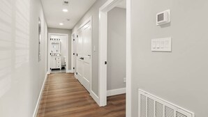 Un pasillo con paredes blancas, suelo de madera y puertas blancas.