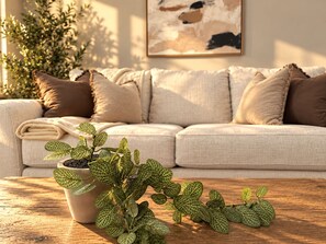 A living room with a sofa, cushions, a coffee table, and a potted plant. - The Neyland Nest D (On UTK campus, free parking) (Knoxville)