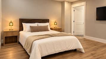 Une chambre à coucher avec un lit, deux tables de chevet, un ventilateur de plafond et une porte.