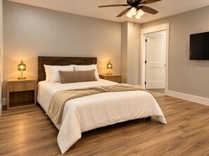 Ein Schlafzimmer mit einem Bett, zwei Nachttischen, einem Deckenventilator und einer Tür.