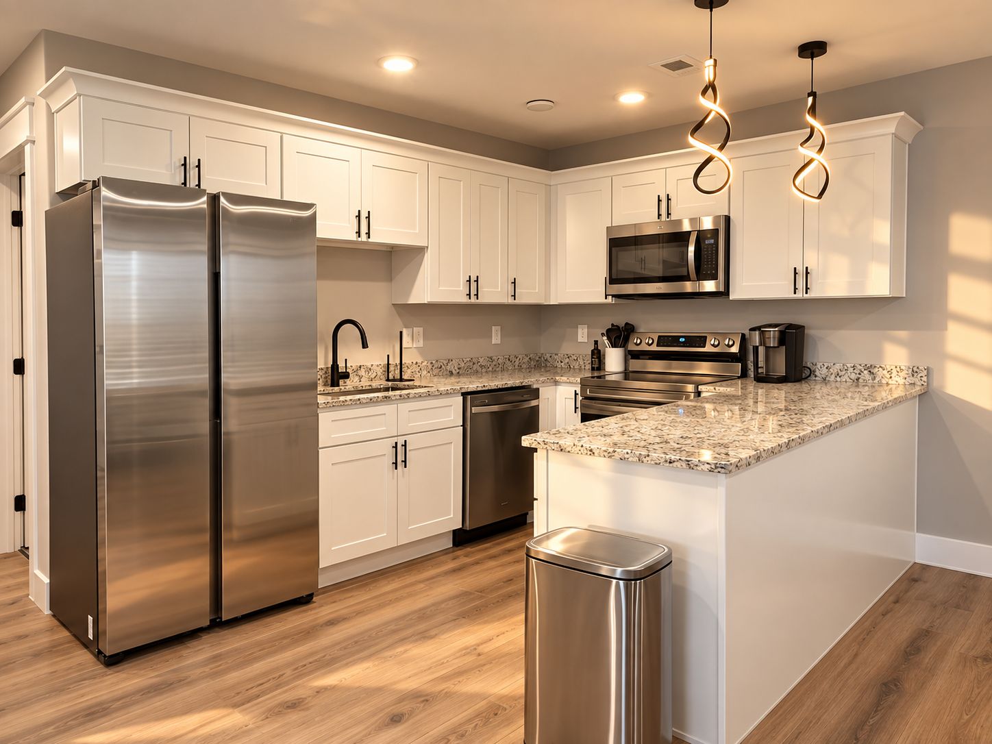 A modern kitchen with stainless steel appliances, white cabinetry, and a granite countertop.