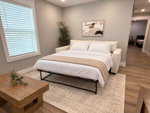 A bedroom with a bed, bedside table, and a window with blinds. - The Neyland Nest D (On UTK campus, free parking) (Knoxville)