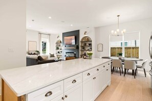 A modern kitchen with a large island, built-in appliances, and a dining area with a chandelier. - Arches on Decatur (2mi to Downtown & UT, King Bed) (Knoxville)