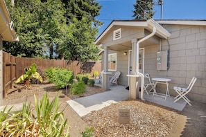 A small house with a patio, a fenced yard, and a sign instructing to clean up after dogs.