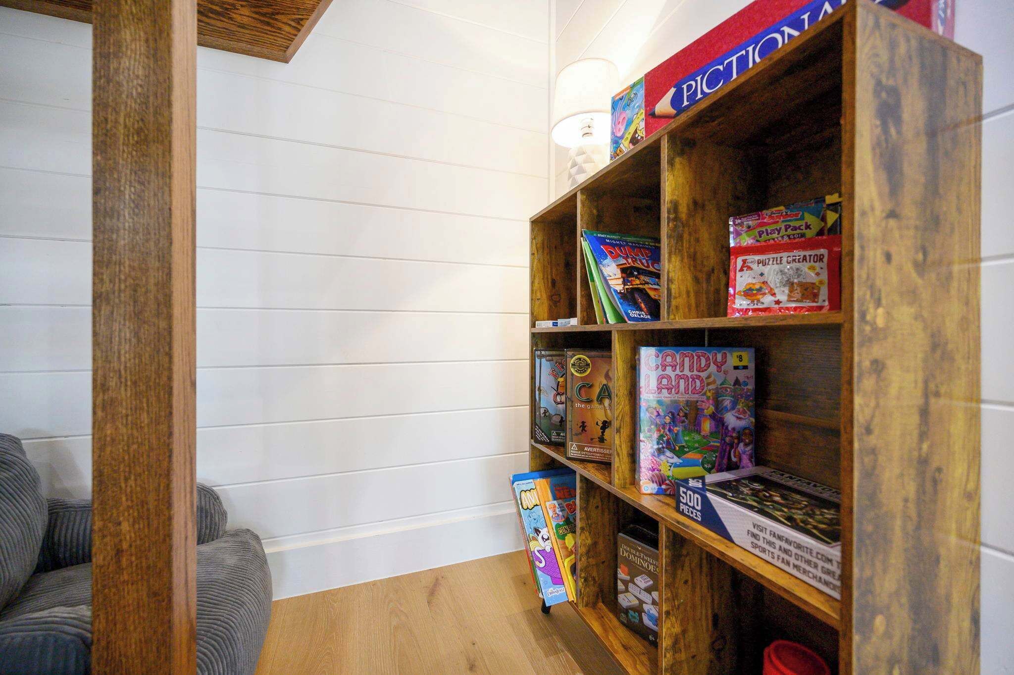 A wooden bookshelf with various board games and puzzles.