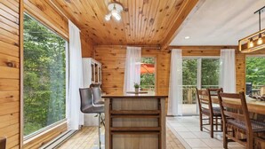 Un intérieur en bois comprenant un coin repas, un comptoir de cuisine et de grandes fenêtres.