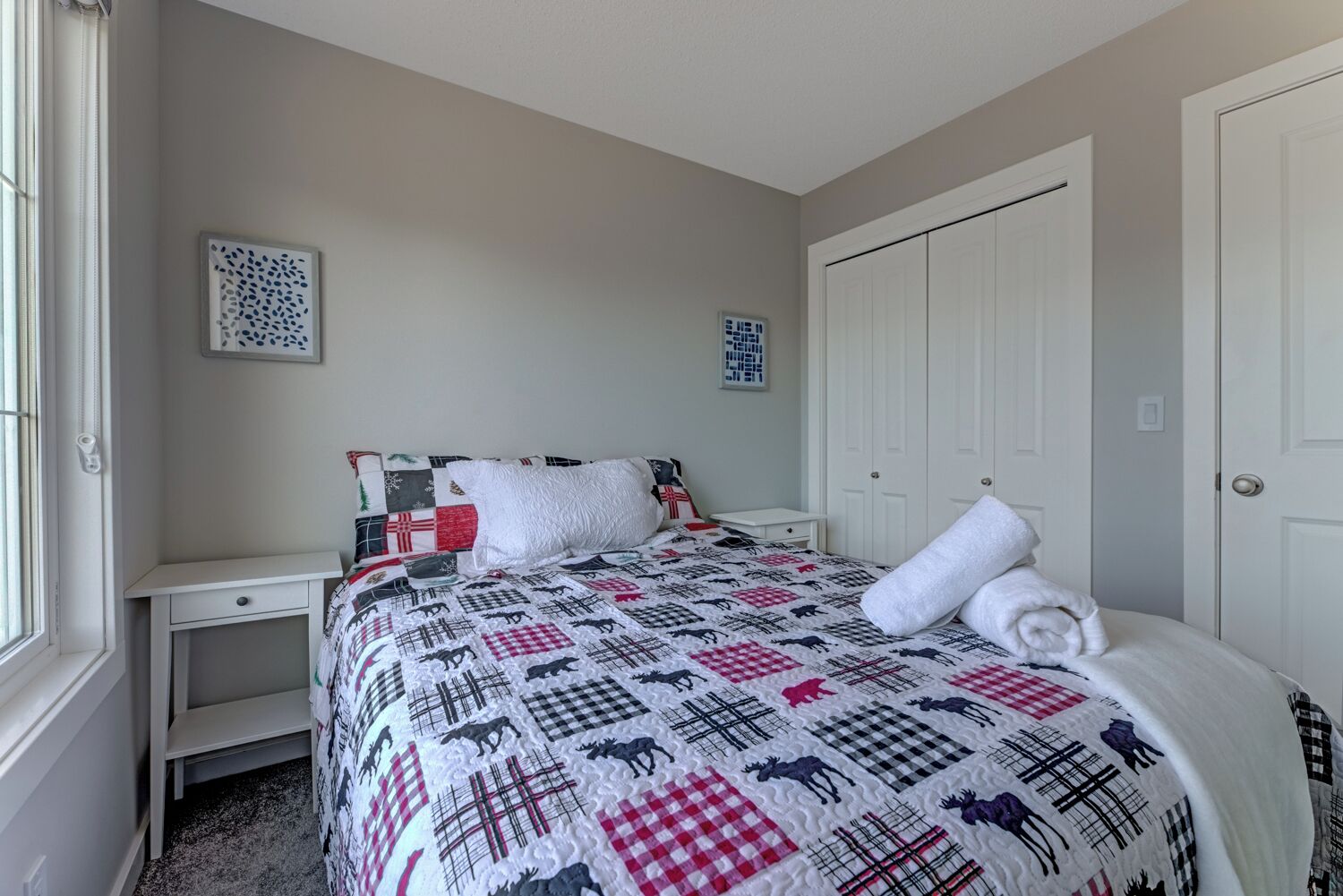 A bedroom with a bed, a nightstand, a dresser, and a closet.