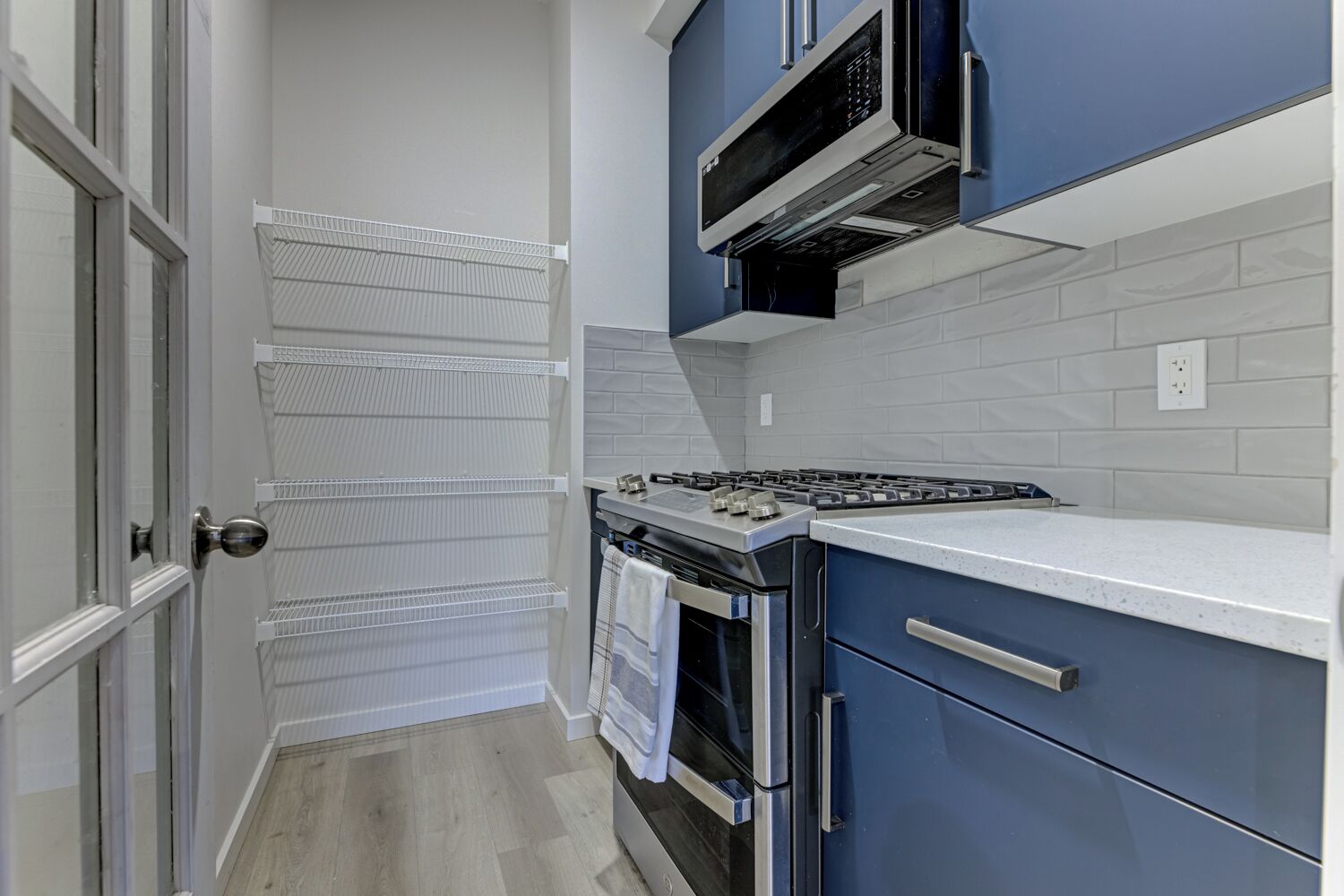 A compact kitchen with a gas stove, oven, and blue cabinets.