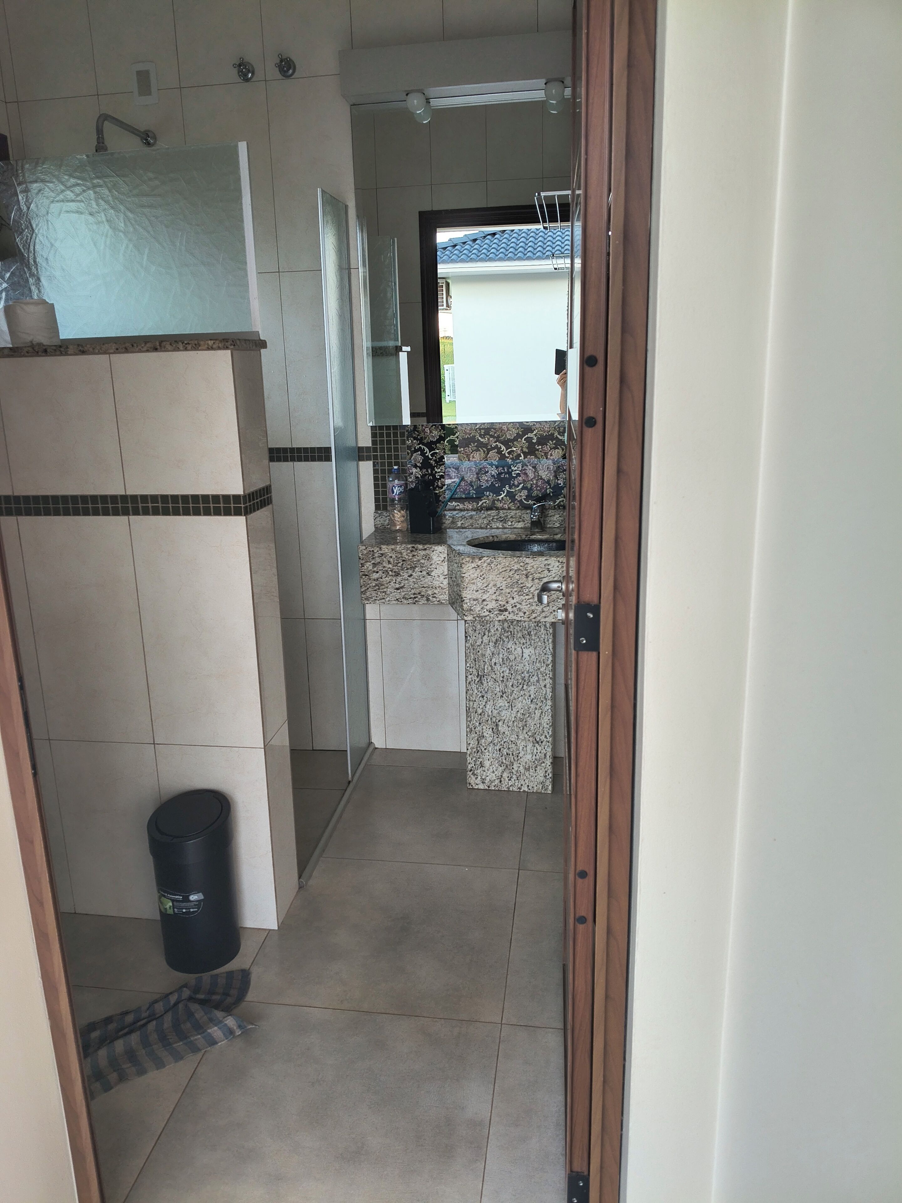 A narrow hallway leading to a bathroom with a shower, a sink, and a tiled floor.. Quiet countryside