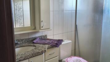 A bathroom with a toilet, sink, mirror, and shower.