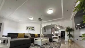 Een ruime woonkamer met een bank, salontafel en een kamerkleed met dessin.