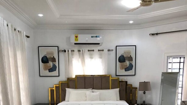 Een slaapkamer met een groot bed, een plafondventilator, een spiegel en kunstwerken aan de wanden.