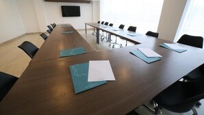 Una sala conferenze con un lungo tavolo, sedie e una televisione a schermo piatto appesa al muro.