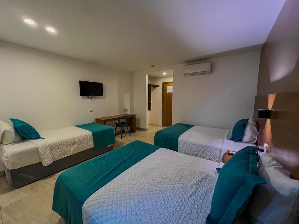 Una habitación de hotel con dos camas individuales, un escritorio, una silla, un televisor y un aire acondicionado.
