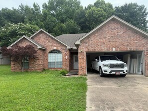 A brick house with a garage, a driveway, and a tree in the front yard. - Peaceful 3-bedroom house with garage and AC in a charming subdivision in Benton. (Benton)