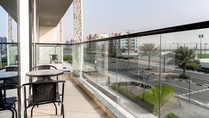 A balcony with a glass railing, a table, and chairs. - Free Housekeeping Visits During Your Stay - Stayshort - Modern 2BR Retreat in Dubai South for 6 (Dubai)