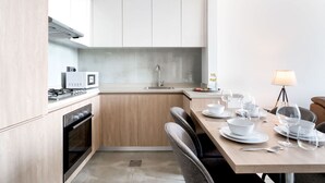 A modern kitchen with white cabinets, a built-in microwave, and a gas stove. - Free Housekeeping Visits During Your Stay - Stayshort - Modern 2BR Retreat in Dubai South for 6 (Dubai)