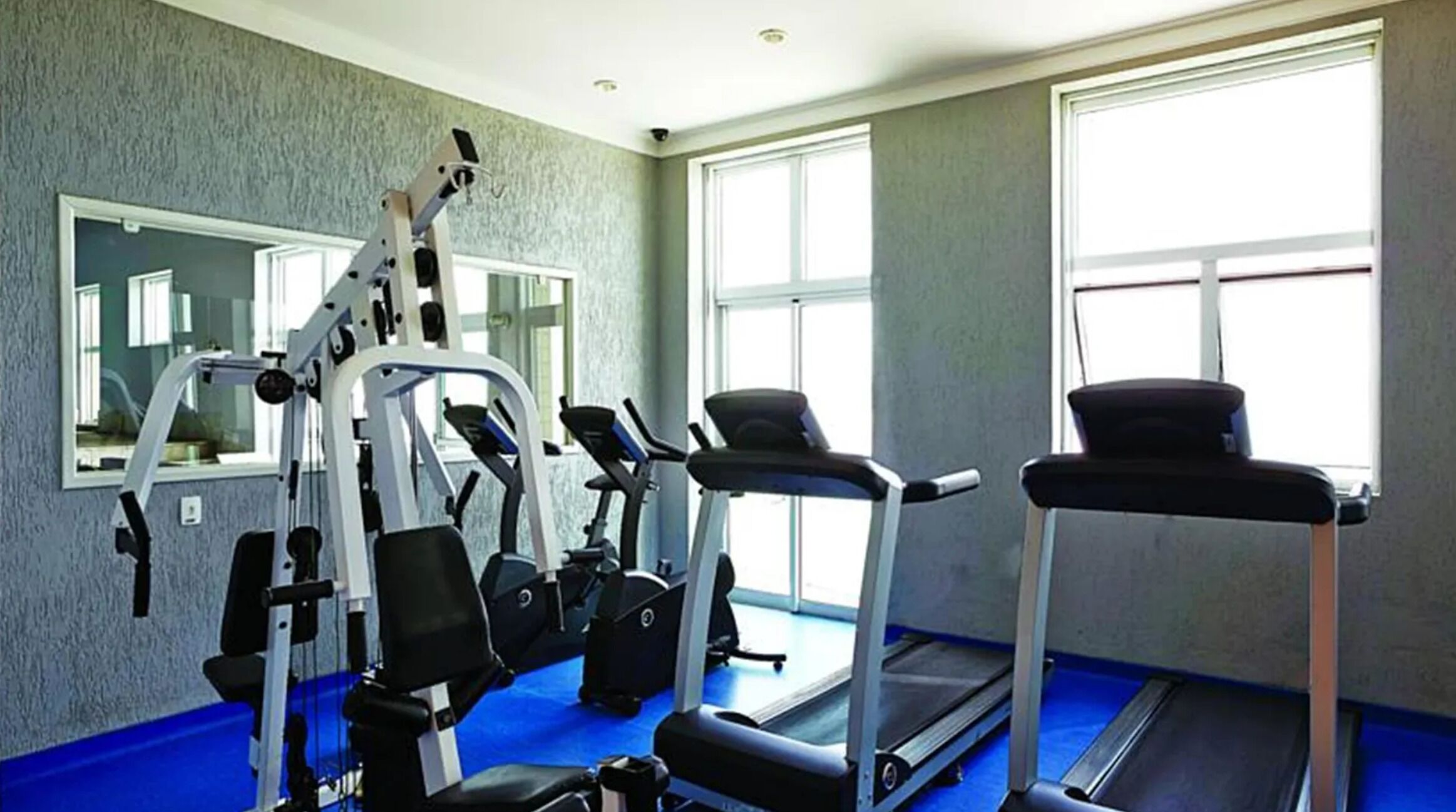 A gym with exercise equipment, a treadmill, and a mirror on the wall.