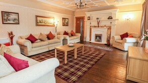 Ein geräumiges Wohnzimmer mit Kamin, mehreren Sofas und einem Couchtisch aus Holz.