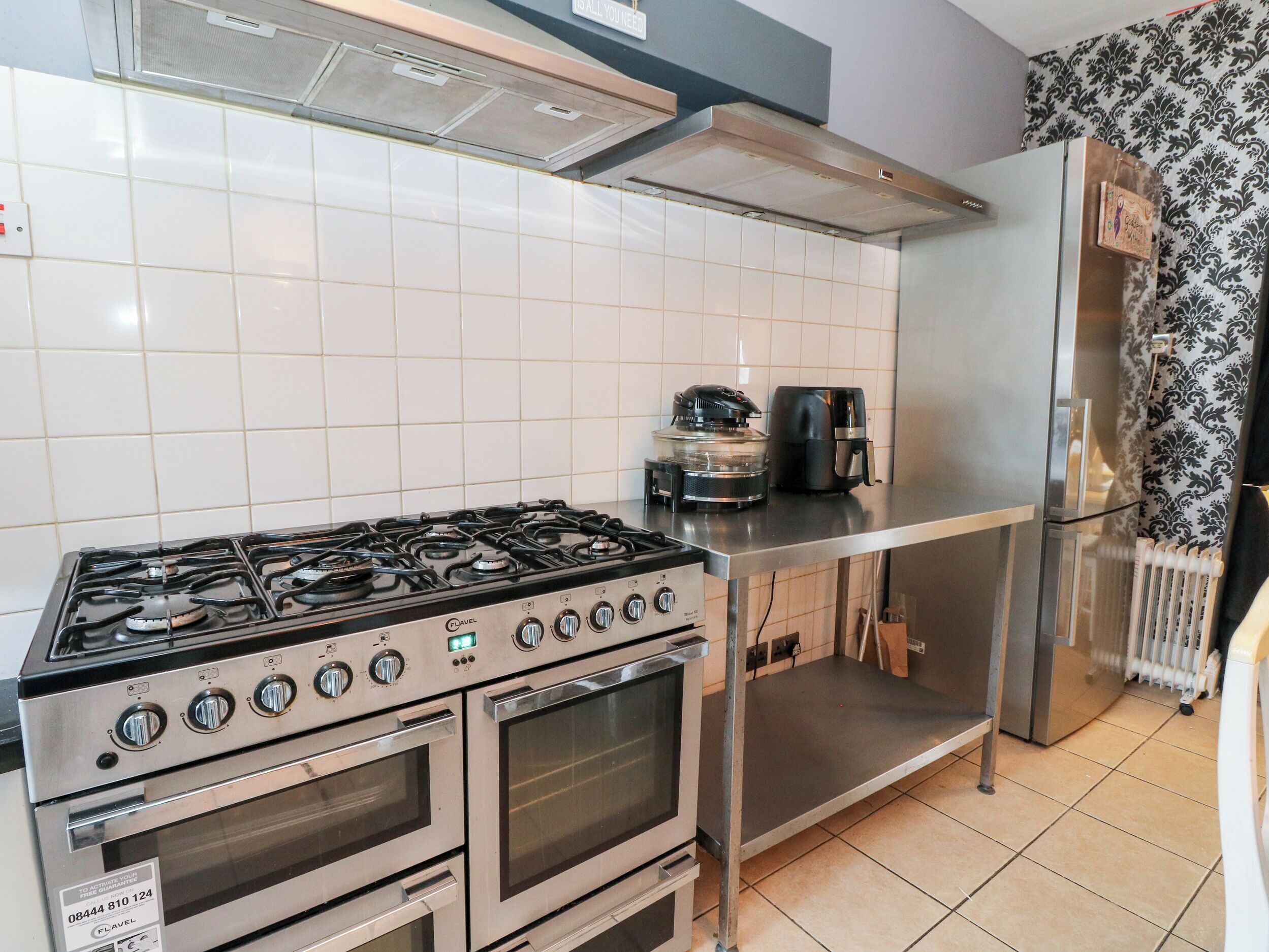 A kitchen with a gas stove, two ovens, a coffee maker, and a refrigerator.