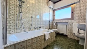 Ein Badezimmer mit einer großen Badewanne, einer Toilette und einem Fenster.