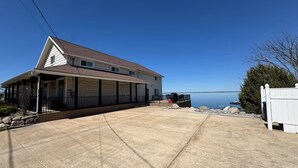 Une maison à deux étages dotée d’un porche abrité, d’une allée en béton et offrant une vue sur un lac.