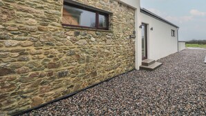 A modern building with a stone facade and a gravel driveway. - The Rookery (Tacumshane)