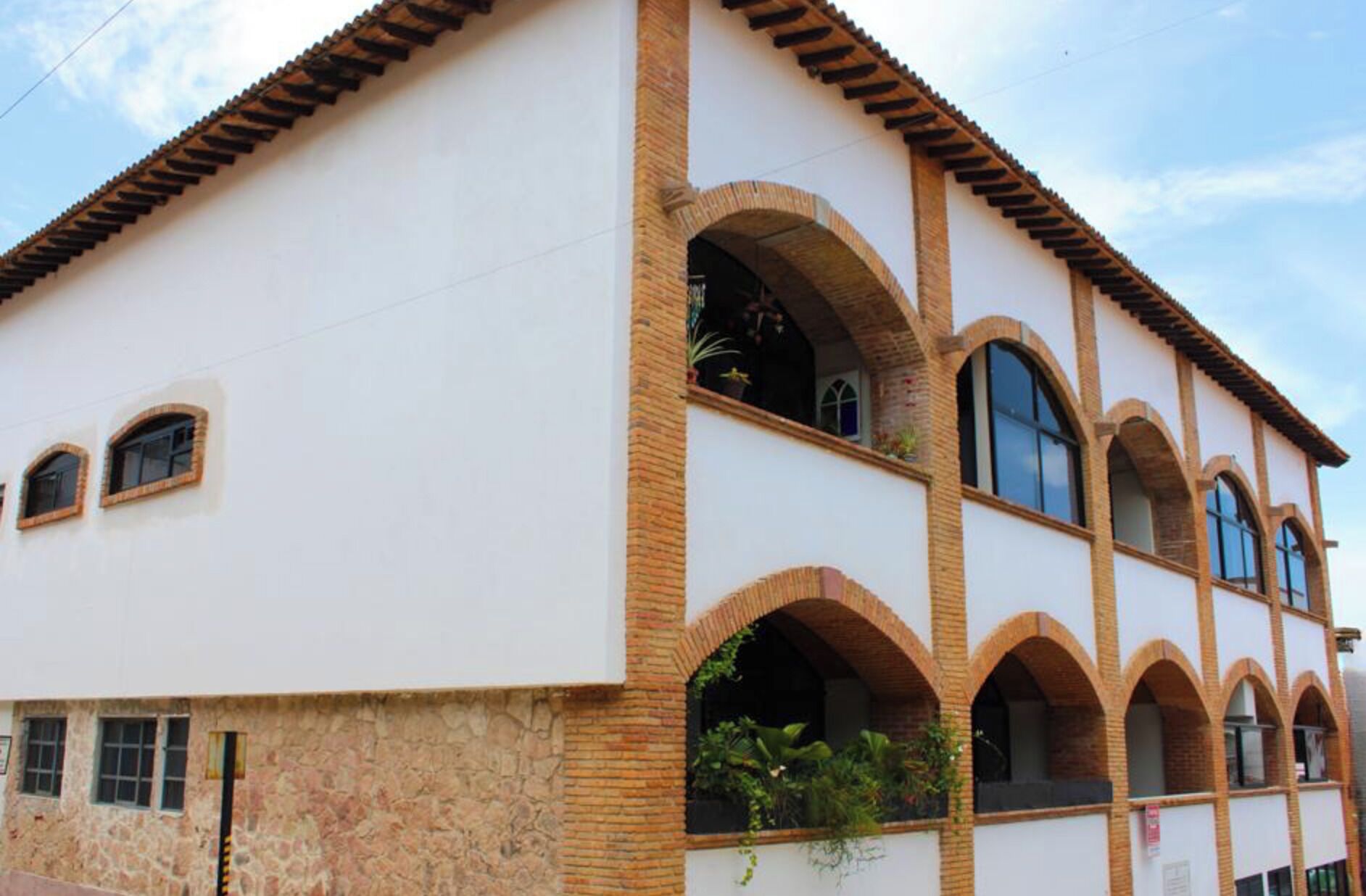 Ein Gebäude mit weißer Fassade, zahlreichen Rundbogenfenstern und einem Ziegeldach.