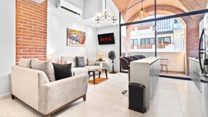 A modern living room with a sofa, a TV, and a kitchen area with a refrigerator. - Perfect 2-bedroom condo Casa Arte with AC in Puerto Vallarta (Puerto Vallarta)