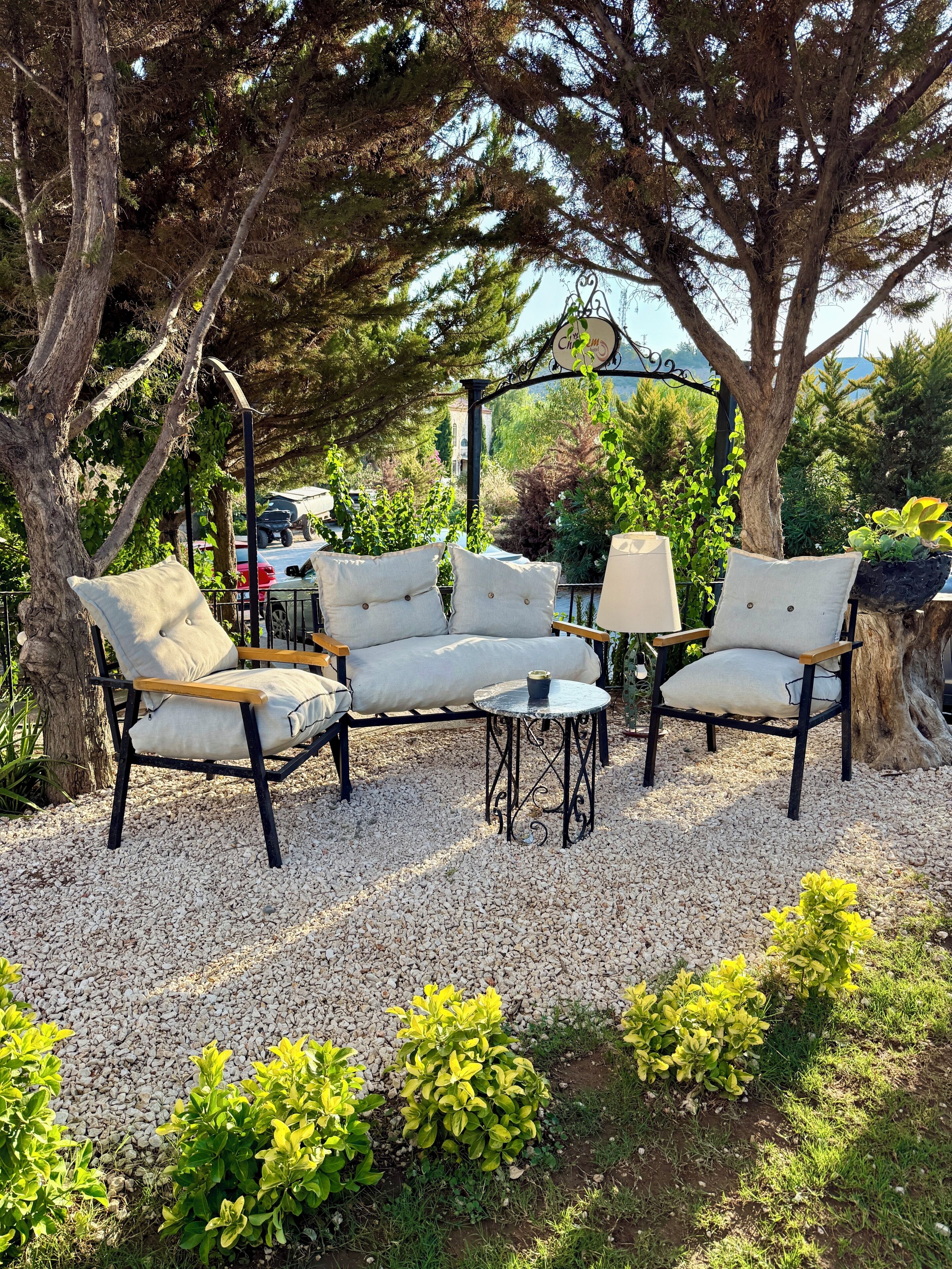 An outdoor seating area with a table and chairs, surrounded by gravel and greenery.