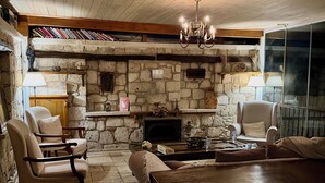Une pièce chaleureuse avec une cheminée en pierre, un plafond en bois et des sièges confortables.