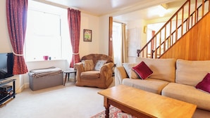 A living room with a sofa, armchair, coffee table, and a television. - Garth Celyn (Porthmadog)