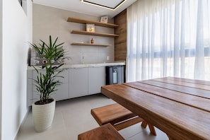A modern kitchen with wooden shelves, a built-in oven, and a potted plant. - APTO 4 Suítes | Espaçoso | Varanda Gourmet | San Martin | Destino BSM 303A (Barra de São Miguel)