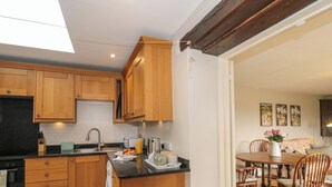 Een moderne keuken met houten kastjes, een inbouwoven en een groot eiland met een spoelbak.