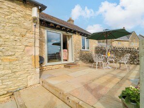 A stone house with a patio, a sliding glass door, and outdoor furniture. - Daisy Bank (Cheltenham)