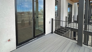 A modern building with a glass door leading to a balcony with a metal railing.