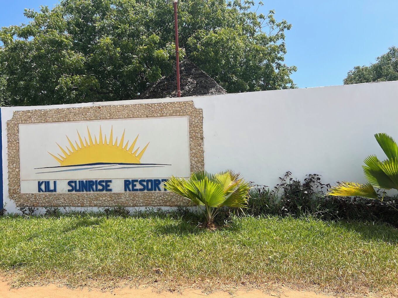 A sign for Kili Sunrise Resort with a sun graphic and text.