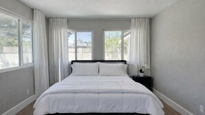 Een slaapkamer met een bed, nachtkastje en een raam met gordijnen.