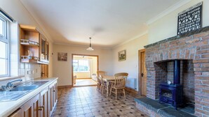 A kitchen with a brick fireplace, wooden cabinets, a tiled floor, and a dining area with chairs.