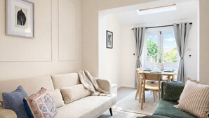 A living room with a sofa, a dining table with chairs, a window with curtains, and a framed picture on the wall. - 3BR Jericho Oxford Home | Walk To The University (Oxfordshire)