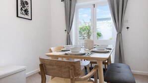 A dining area with a table set for four, chairs, a bench, a framed artwork on the wall, and a window with curtains. - 3BR Jericho Oxford Home | Walk To The University (Oxfordshire)