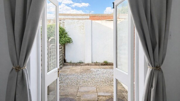 An open doorway leading to a courtyard with a gravel path and a brick wall. - 3BR Jericho Oxford Home | Walk To The University (Oxfordshire)