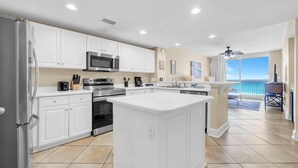 A kitchen with white cabinets, stainless steel appliances, and a large island. - Majestic Beach Towers 2-305 (Panama City Beach)
