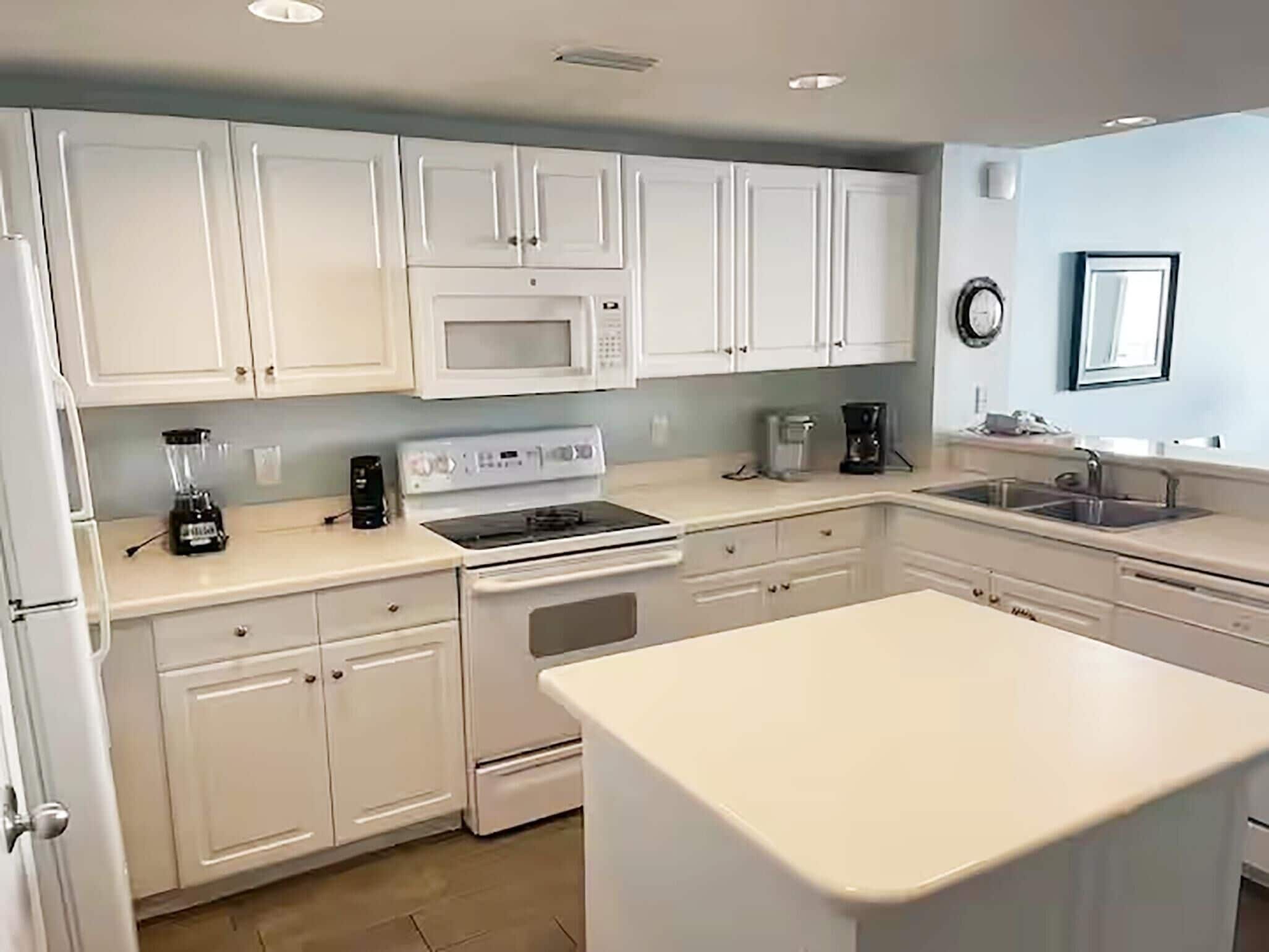 A modern kitchen with white cabinets, a microwave, stove, and a large island.