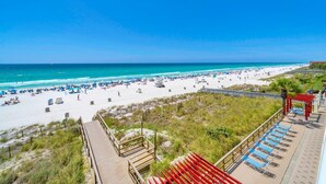 A beach with a wooden boardwalk, beach umbrellas, and lounge chairs. - Majestic Beach Towers 2-305 (Panama City Beach)